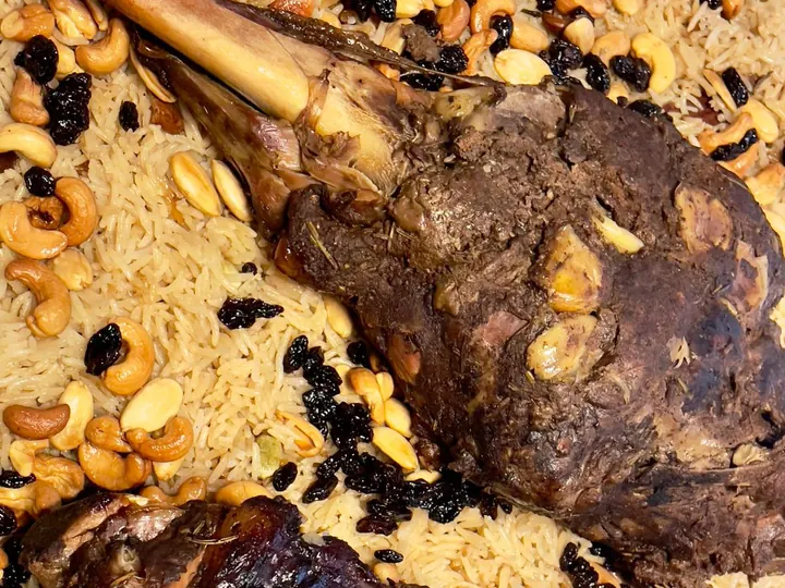 Roasted lamb legs served over rice with nuts and raisins.