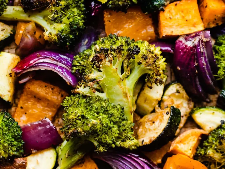 Roasted mixed vegetables with broccoli, zucchini, red onion and orange vegetable pieces.